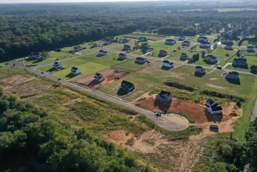 An aerial of a new-home neighborhood going up among woods, with houses on cleared pads